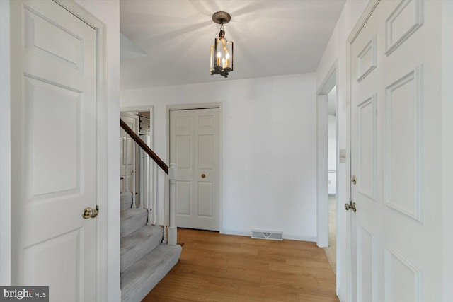 entryway with visible vents, a notable chandelier, stairway, light wood finished floors, and baseboards