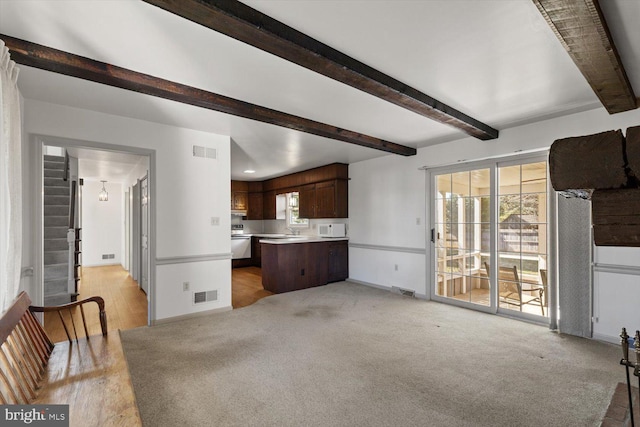 unfurnished living room featuring visible vents, baseboards, and beamed ceiling