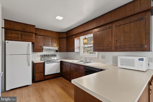 kitchen featuring under cabinet range hood, light countertops, a peninsula, white appliances, and a sink