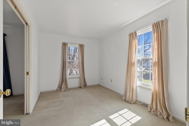 unfurnished bedroom featuring carpet flooring, multiple windows, and visible vents