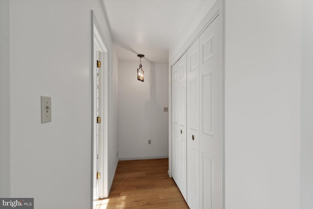 hall with light wood-type flooring and baseboards