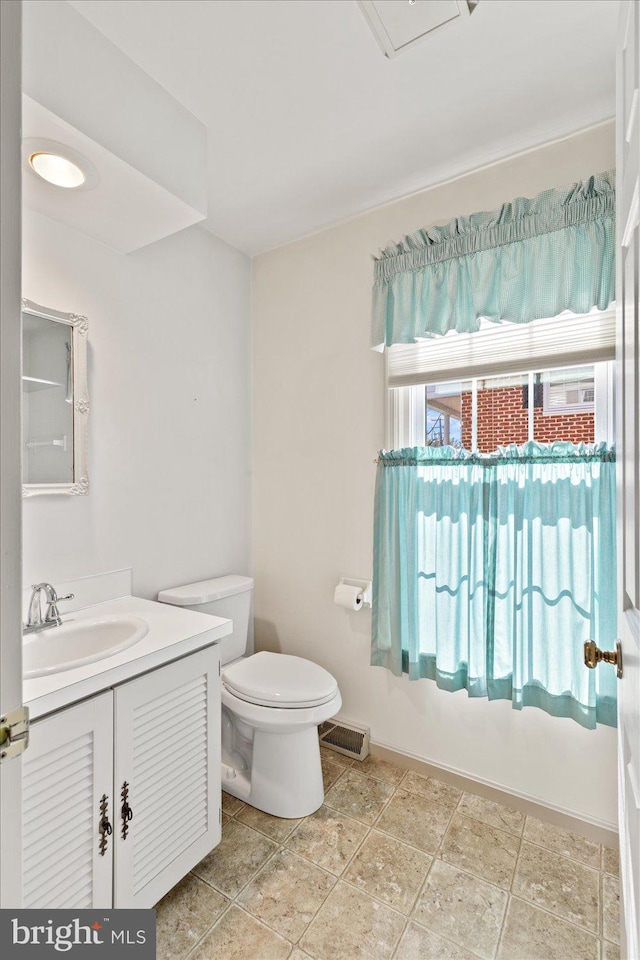 bathroom with vanity, toilet, baseboards, and visible vents