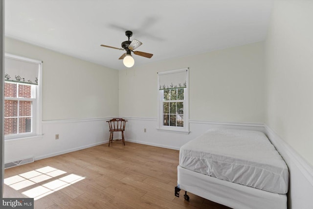 bedroom featuring ceiling fan, wood finished floors, visible vents, and baseboards