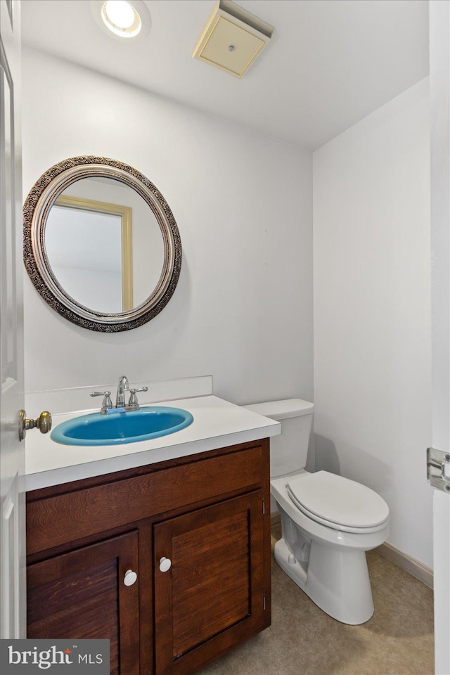 half bath with vanity, toilet, and baseboards