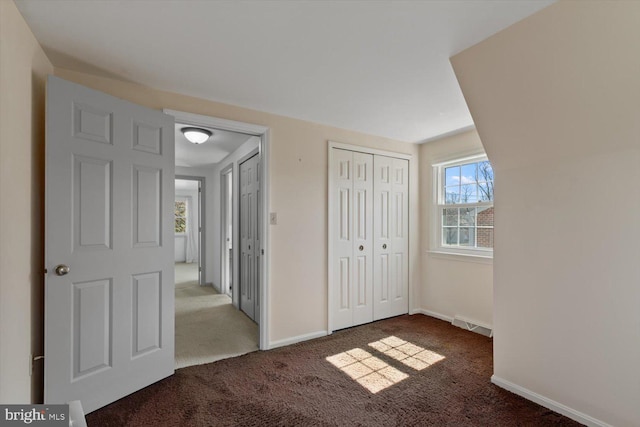 unfurnished bedroom featuring baseboards, carpet floors, and a closet