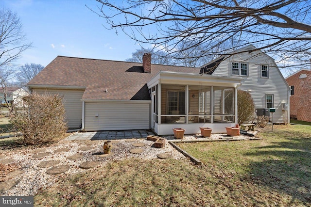 back of property featuring a chimney, a lawn, a shingled roof, and a sunroom