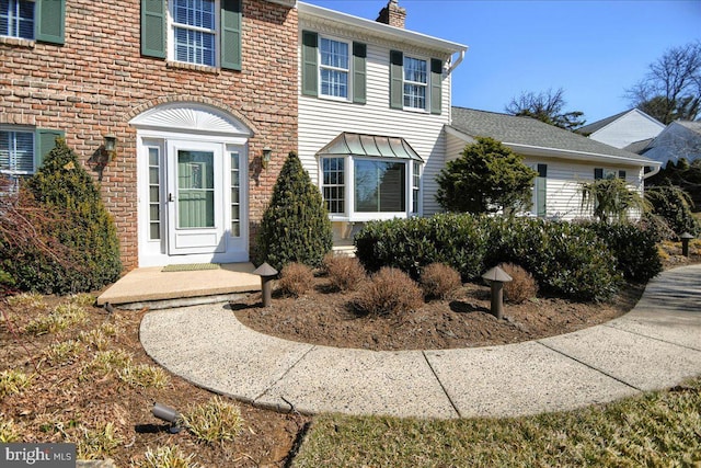 exterior space with brick siding and a chimney