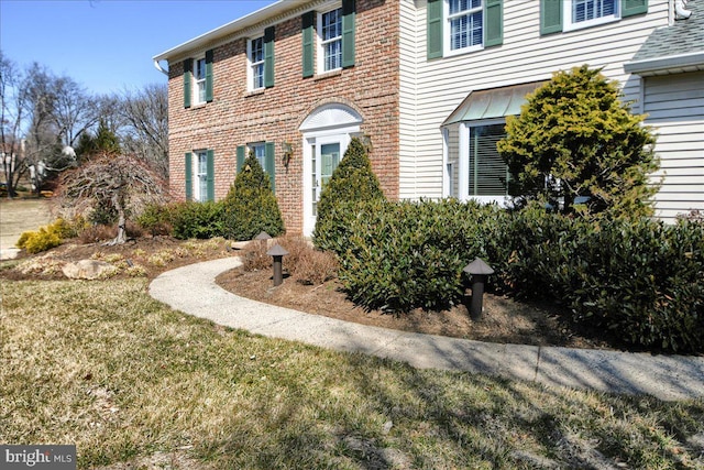 exterior space with brick siding and a lawn