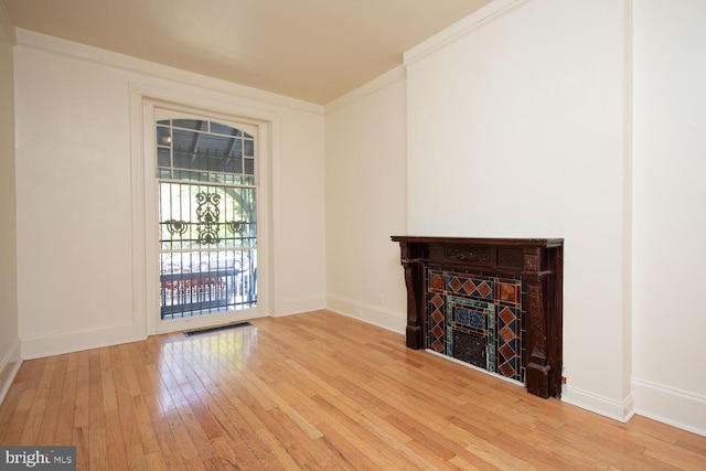 unfurnished living room featuring visible vents, crown molding, baseboards, a tiled fireplace, and wood-type flooring