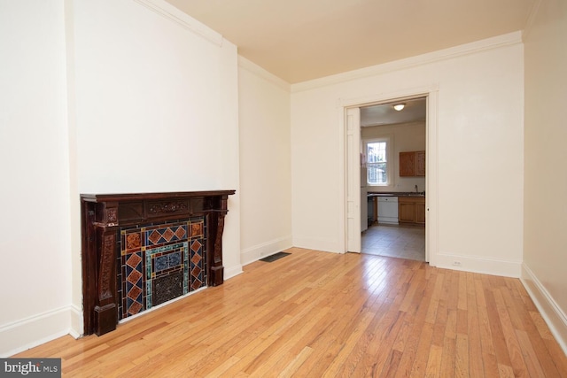 unfurnished living room featuring visible vents, crown molding, baseboards, a tile fireplace, and hardwood / wood-style flooring