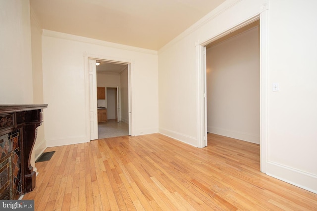 interior space featuring visible vents, baseboards, crown molding, and light wood-style floors