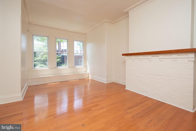 unfurnished living room featuring baseboards, light wood-style floors, and ornamental molding