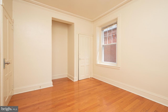 unfurnished bedroom with light wood-style flooring, baseboards, and ornamental molding