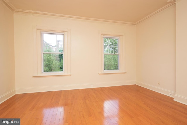 empty room featuring light wood-style flooring, crown molding, and baseboards