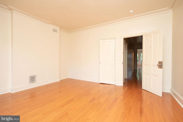 spare room featuring visible vents, light wood-style flooring, and ornamental molding