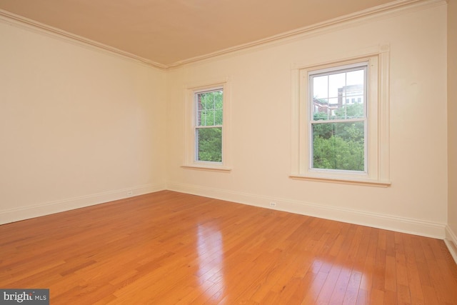 unfurnished room featuring light wood-style flooring, baseboards, and ornamental molding