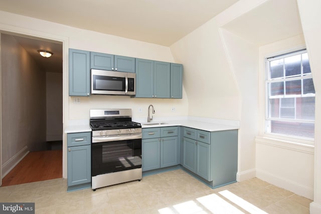 kitchen featuring a sink, stainless steel appliances, a wealth of natural light, and light countertops