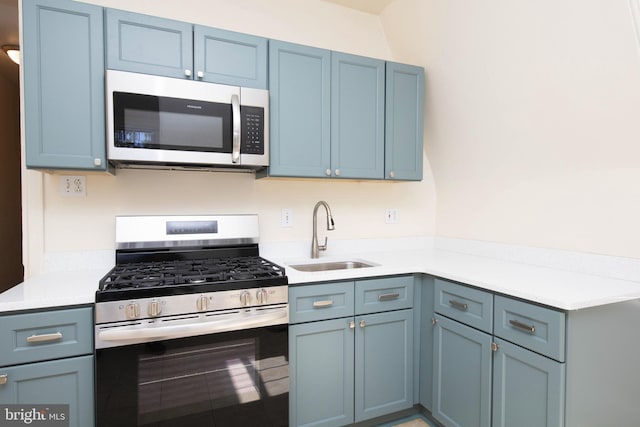 kitchen featuring a sink, stainless steel appliances, blue cabinets, and light countertops