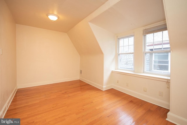 bonus room featuring baseboards, light wood-style flooring, and vaulted ceiling