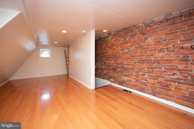 additional living space featuring visible vents, recessed lighting, brick wall, and hardwood / wood-style floors