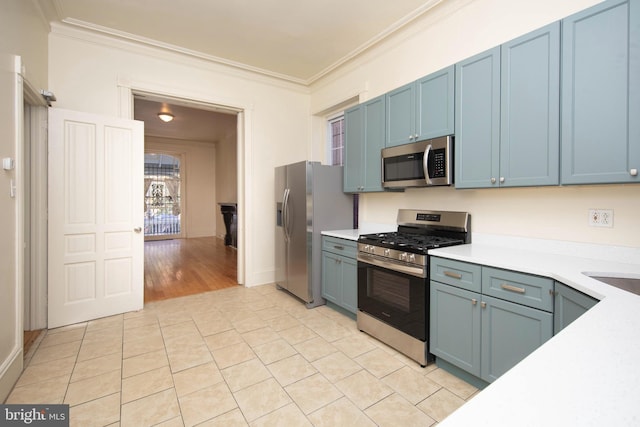 kitchen featuring blue cabinetry, stainless steel appliances, ornamental molding, and light countertops