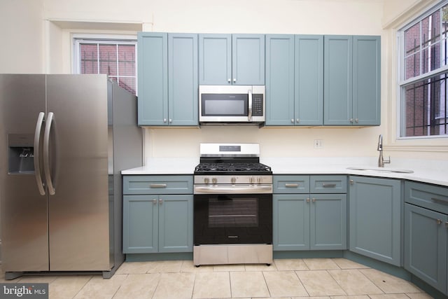 kitchen featuring a sink, light countertops, plenty of natural light, and stainless steel appliances