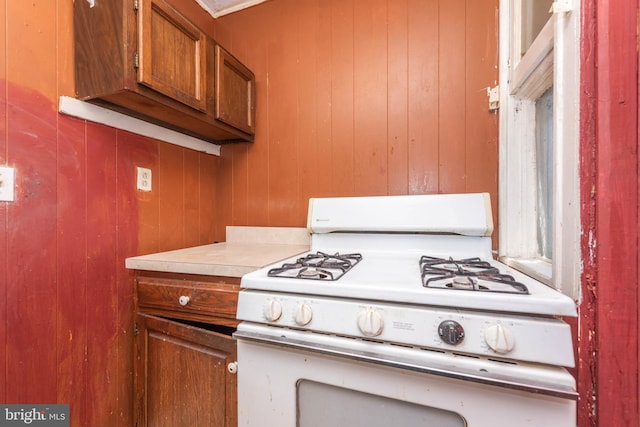 kitchen featuring light countertops, gas range gas stove, and brown cabinets