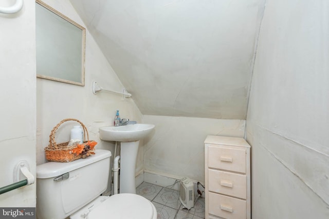 half bathroom with toilet, lofted ceiling, and a sink