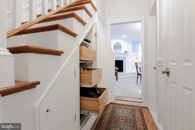 stairway with wood finished floors and a fireplace with raised hearth