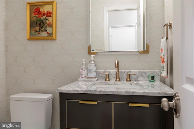 bathroom featuring wallpapered walls, toilet, and vanity