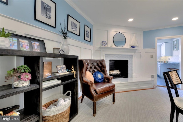 sitting room with a decorative wall, a fireplace, carpet, and ornamental molding