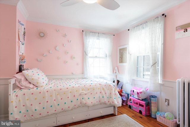 bedroom with wainscoting, radiator, wood finished floors, and ornamental molding