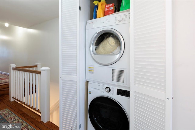 laundry room featuring stacked washer and dryer, wood finished floors, and laundry area