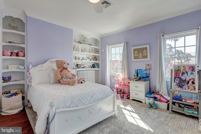 bedroom with visible vents, wood finished floors, and ornamental molding