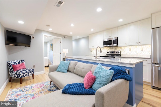 living area featuring light wood finished floors and recessed lighting