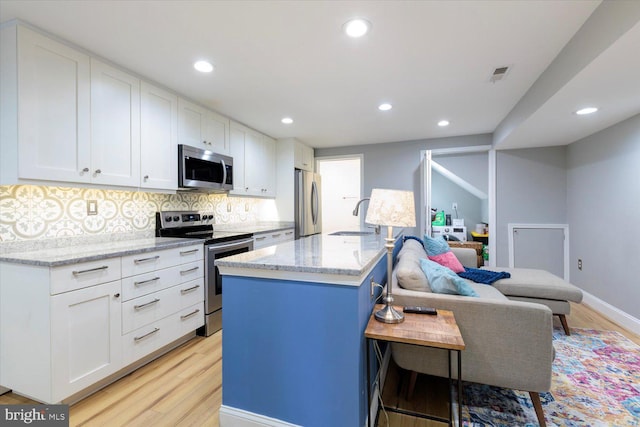 kitchen featuring visible vents, light wood-style flooring, a sink, white cabinets, and appliances with stainless steel finishes