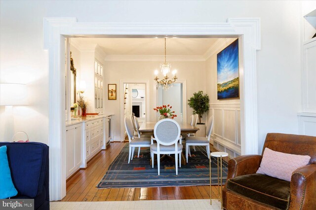 dining space featuring a decorative wall, a notable chandelier, hardwood / wood-style floors, and ornamental molding