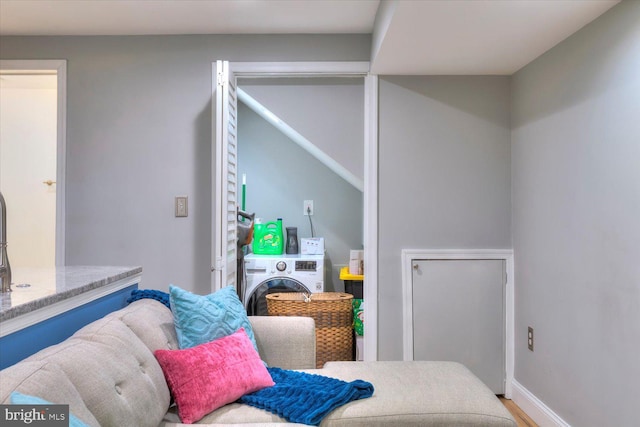 bedroom featuring baseboards, washer / dryer, and wood finished floors