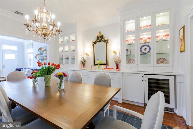 dining room with wine cooler, a chandelier, crown molding, and wood finished floors
