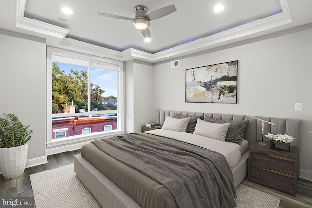 bedroom featuring visible vents, crown molding, a raised ceiling, and wood finished floors