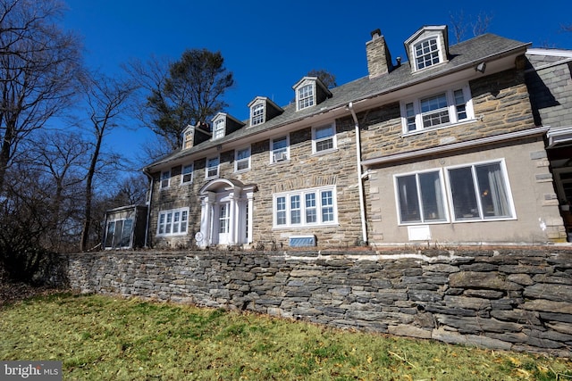 view of front of property featuring stone siding and a chimney