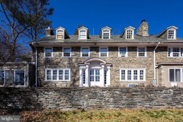 view of front of property featuring stone siding and a chimney