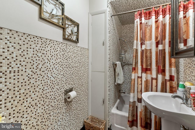 full bathroom with a sink, a wainscoted wall, tile walls, and shower / bath combo