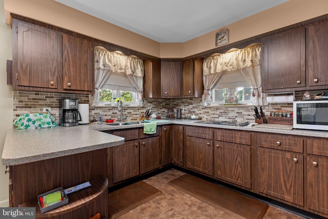 kitchen with decorative backsplash, light countertops, white microwave, and a sink