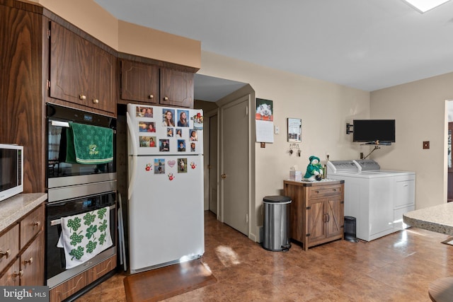 kitchen featuring stainless steel double oven, independent washer and dryer, light countertops, and freestanding refrigerator