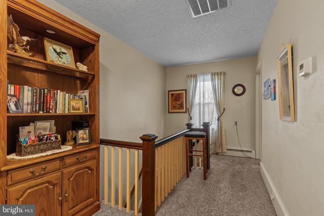 hall featuring a textured ceiling, an upstairs landing, visible vents, and light carpet