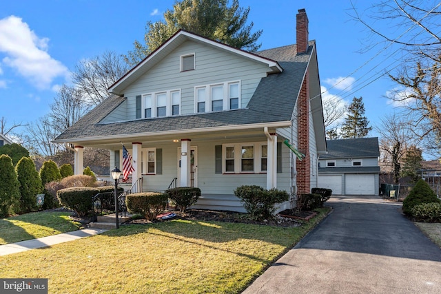 bungalow featuring a front yard, a porch, a shingled roof, a chimney, and an outdoor structure