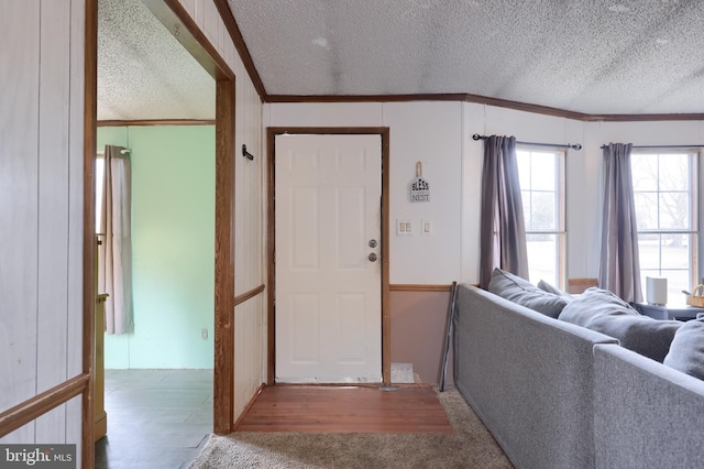 entryway featuring crown molding, wood finished floors, and a textured ceiling