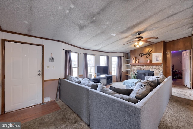 living area featuring a textured ceiling, a fireplace, crown molding, and wood walls