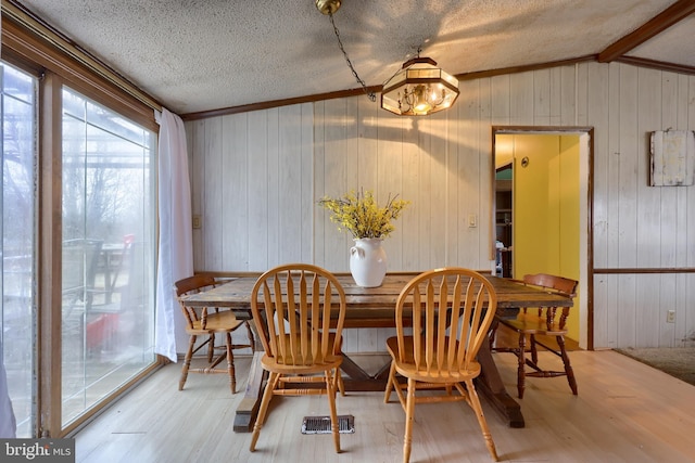 dining room with vaulted ceiling, a textured ceiling, and wood finished floors